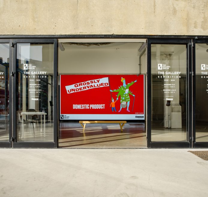 The outside of The Gallery's retrospective exhibition. The digital screen inside is showing ‘GROSSLY UNDERVALUED DOMESTIC PRODUCT’ (2022) by Bobby Baker.